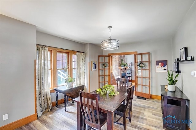 dining room with light wood-style floors, baseboards, and an inviting chandelier