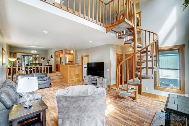 living room with recessed lighting, a towering ceiling, light wood-style floors, baseboards, and stairs