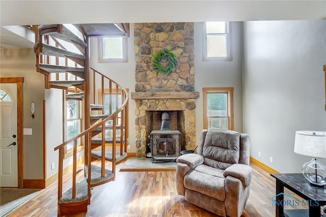 living room featuring a wood stove, stairway, baseboards, and wood finished floors