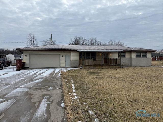 ranch-style house with metal roof, a garage, covered porch, driveway, and a front yard