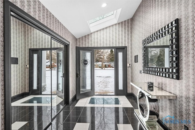 doorway with vaulted ceiling with skylight, granite finish floor, and wallpapered walls