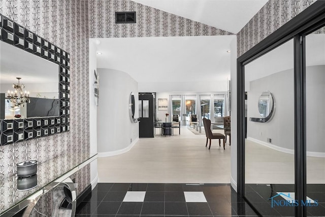 hall featuring wallpapered walls, baseboards, visible vents, lofted ceiling, and a chandelier