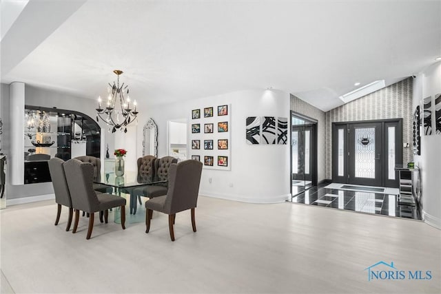 dining room featuring baseboards, vaulted ceiling, light wood-type flooring, an inviting chandelier, and wallpapered walls