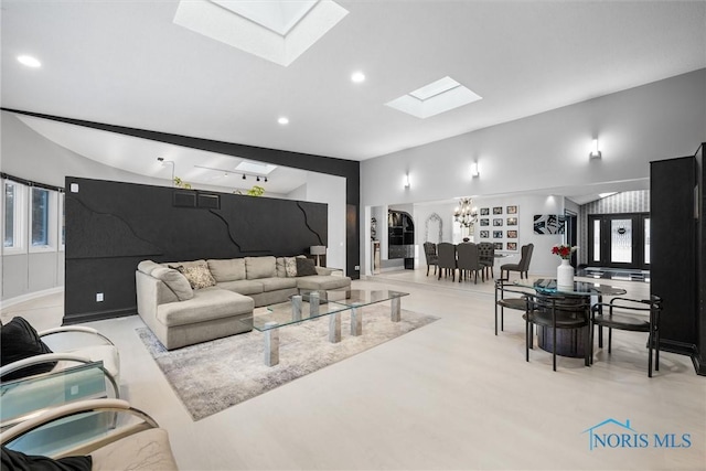 living room with lofted ceiling with skylight, recessed lighting, and a chandelier