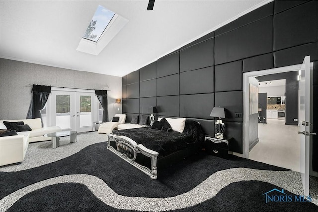 bedroom with vaulted ceiling with skylight, french doors, and a decorative wall