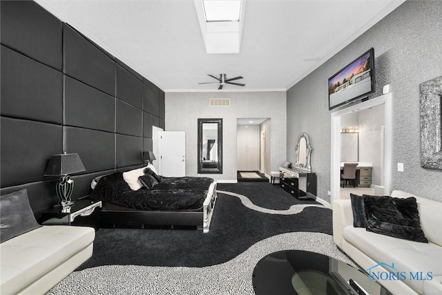 bedroom featuring a skylight, visible vents, ornamental molding, a ceiling fan, and carpet flooring