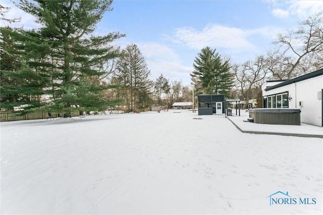 yard covered in snow featuring fence and a hot tub