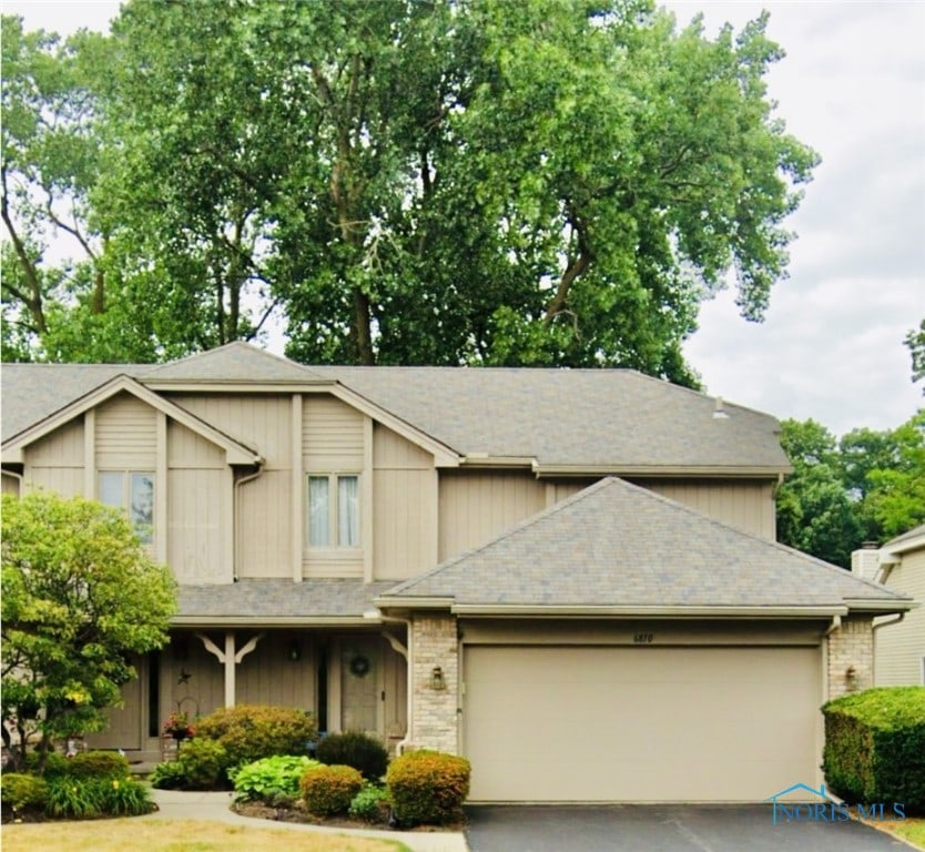 view of front of property featuring an attached garage, aphalt driveway, and brick siding