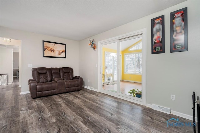 living area featuring a textured ceiling, dark wood-type flooring, visible vents, and baseboards