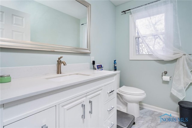 bathroom featuring toilet, marble finish floor, vanity, and baseboards