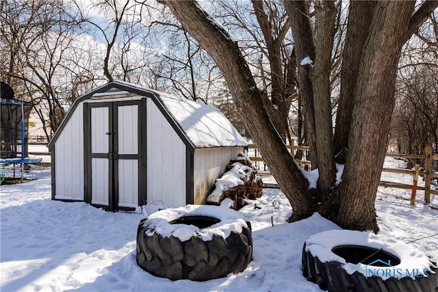 snow covered structure featuring a trampoline and fence