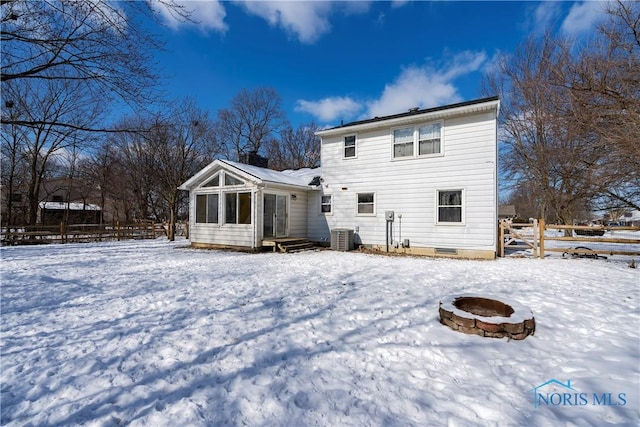 snow covered rear of property with central AC, an outdoor fire pit, crawl space, and fence