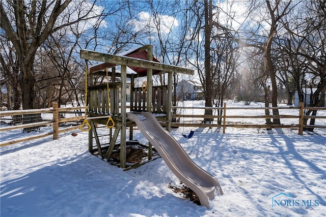 snow covered playground with a playground and fence