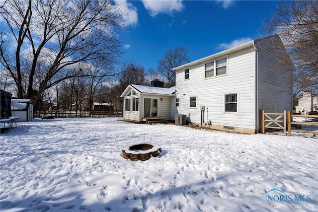 snow covered rear of property with entry steps, cooling unit, fence, and a fire pit