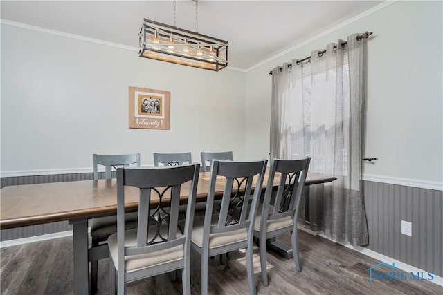 dining space with an inviting chandelier, ornamental molding, dark wood finished floors, and wainscoting