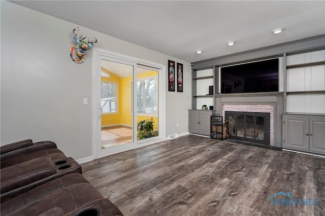 living room with a brick fireplace, a textured ceiling, baseboards, and dark wood-style flooring