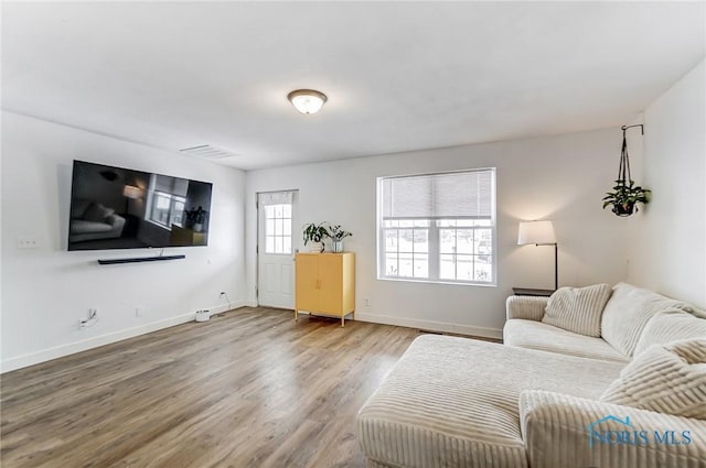 living area with wood finished floors, visible vents, and baseboards