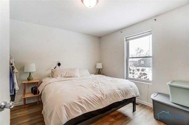 bedroom with multiple windows, baseboards, and wood finished floors