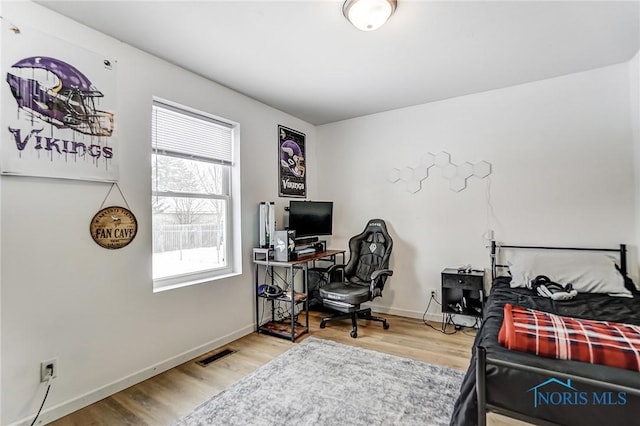 bedroom with wood finished floors, visible vents, and baseboards