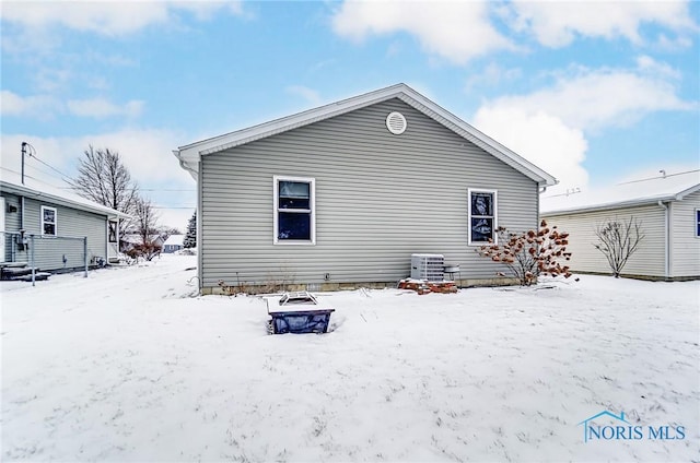 snow covered house featuring an outdoor fire pit and central air condition unit