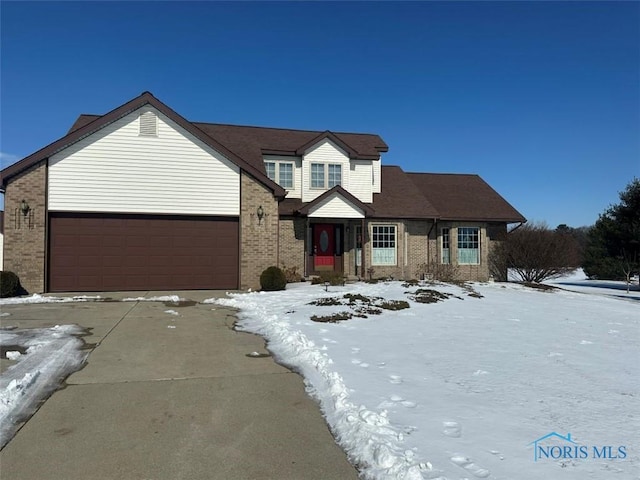 traditional-style home featuring a garage, concrete driveway, and brick siding