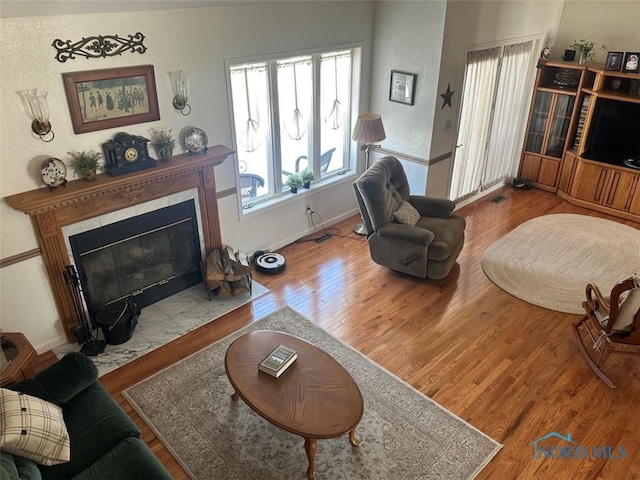 living room with a fireplace with flush hearth, baseboards, and wood finished floors