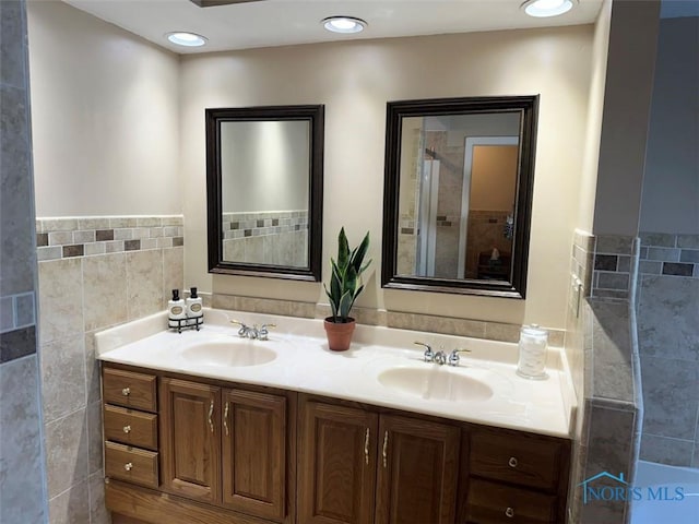 bathroom with a sink, tile walls, and double vanity