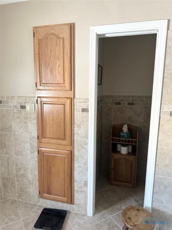 bathroom featuring a wainscoted wall, tile patterned flooring, and tile walls