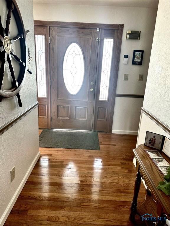 foyer with a textured wall, dark wood finished floors, and baseboards