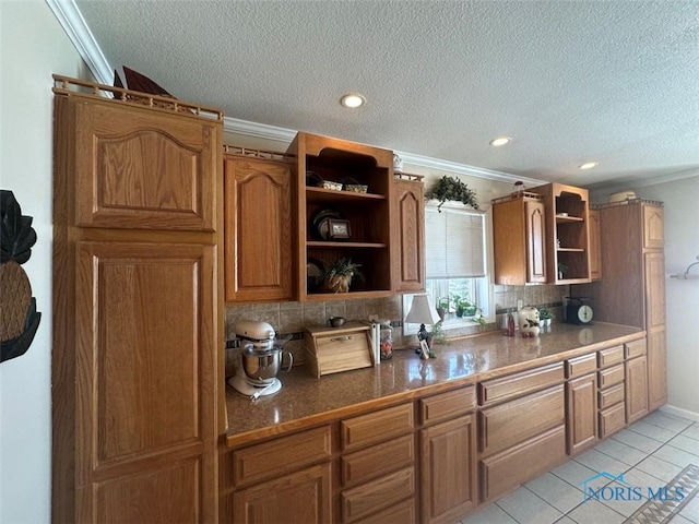 kitchen with open shelves, dark countertops, backsplash, ornamental molding, and brown cabinetry