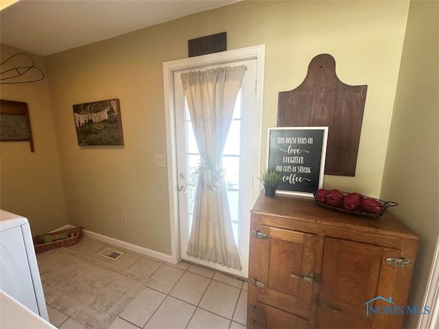 doorway to outside with light tile patterned flooring, visible vents, and baseboards