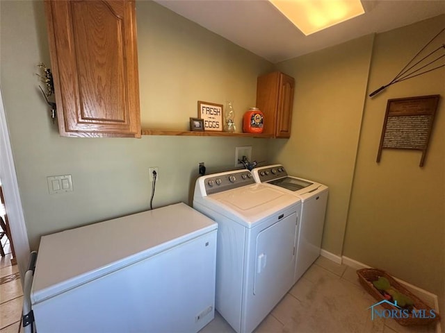 clothes washing area featuring light tile patterned flooring, washing machine and clothes dryer, and cabinet space