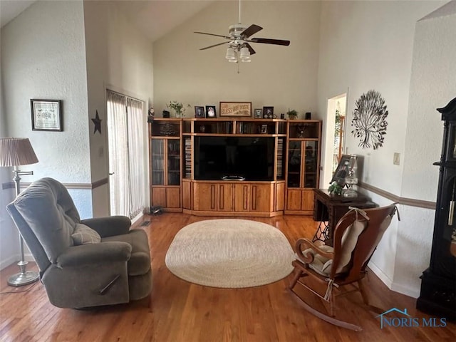 living room featuring high vaulted ceiling, wood finished floors, a ceiling fan, and baseboards