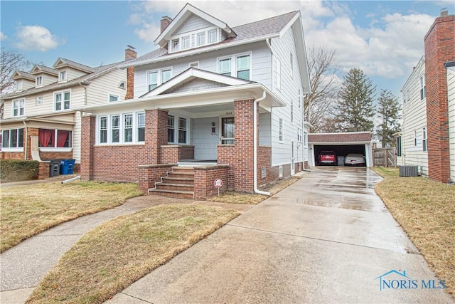 traditional style home featuring a garage, brick siding, covered porch, and a front yard