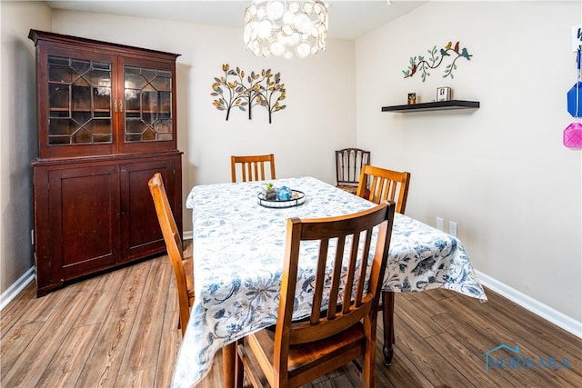 dining space featuring light wood-type flooring, baseboards, and a notable chandelier