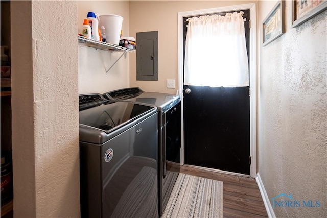 laundry room featuring laundry area, electric panel, baseboards, dark wood finished floors, and washing machine and clothes dryer