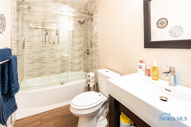 full bathroom with toilet, a sink, combined bath / shower with glass door, and wood finished floors