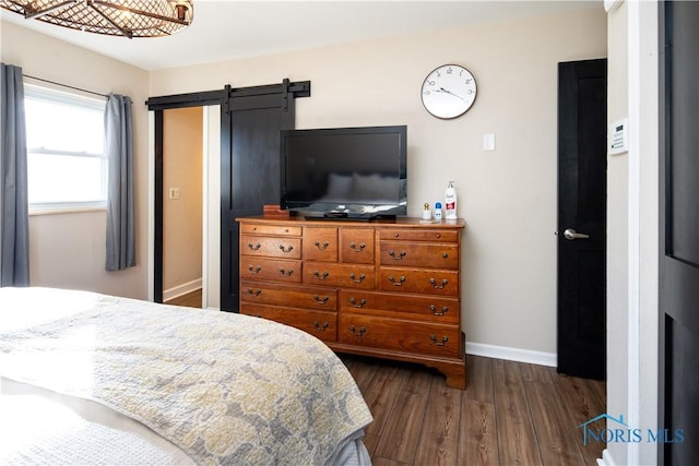 bedroom featuring a barn door, baseboards, and dark wood-style flooring