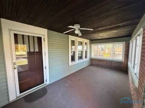 unfurnished sunroom featuring wood ceiling and a ceiling fan