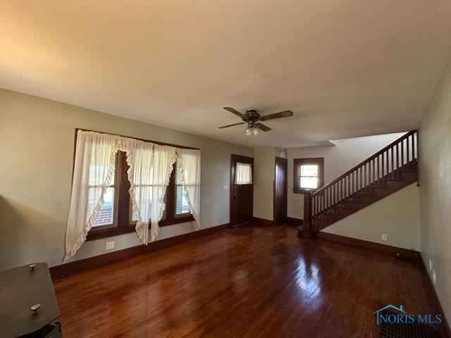 entrance foyer with a ceiling fan, dark wood finished floors, baseboards, and stairs