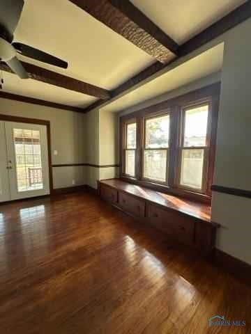 empty room featuring dark wood-type flooring, beamed ceiling, and plenty of natural light