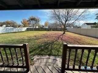 wooden terrace with a fenced backyard and a lawn