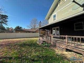 view of home's exterior with fence, a deck, and a lawn