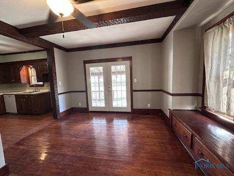 interior space featuring beam ceiling, baseboards, dark wood-style flooring, and french doors