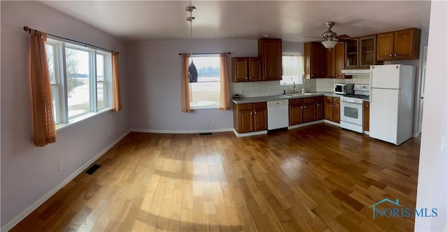 kitchen with light countertops, a sink, wood finished floors, white appliances, and under cabinet range hood