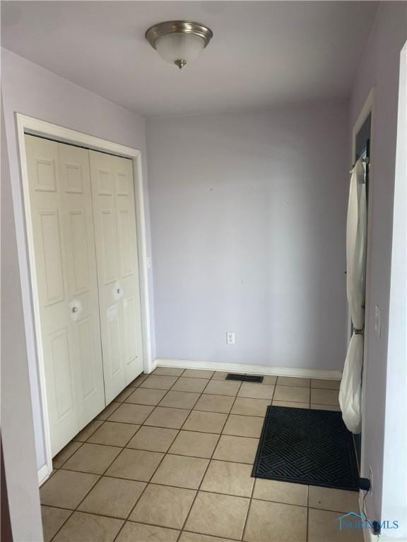 unfurnished bedroom featuring a closet, light tile patterned flooring, visible vents, and baseboards