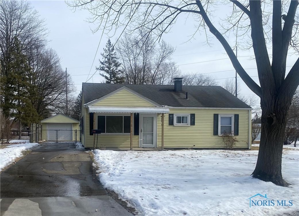 view of front of property featuring a garage, a shingled roof, a chimney, and an outdoor structure