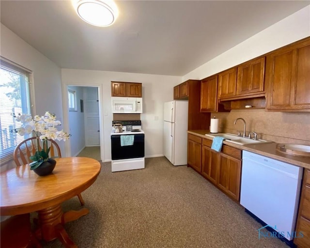 kitchen featuring light countertops, white appliances, brown cabinets, and a sink