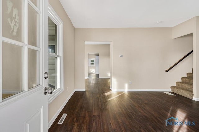 interior space featuring dark wood-style floors, stairway, visible vents, and baseboards