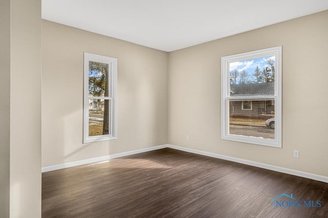 unfurnished room with a healthy amount of sunlight, baseboards, and dark wood finished floors